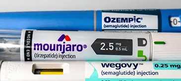 A close-up of three different weight loss injection pens: Ozempic, Mounjaro, and Wegovy
