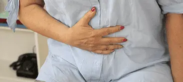 A patient holding his hand on his stomach, indicating potential digestive discomfort from Mounjaro side effects