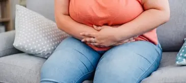 A patient holding their stomach, illustrating the digestive discomfort that can come with slimming injection side effects